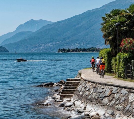 A group of people cycling on the Lake Como waterfront.