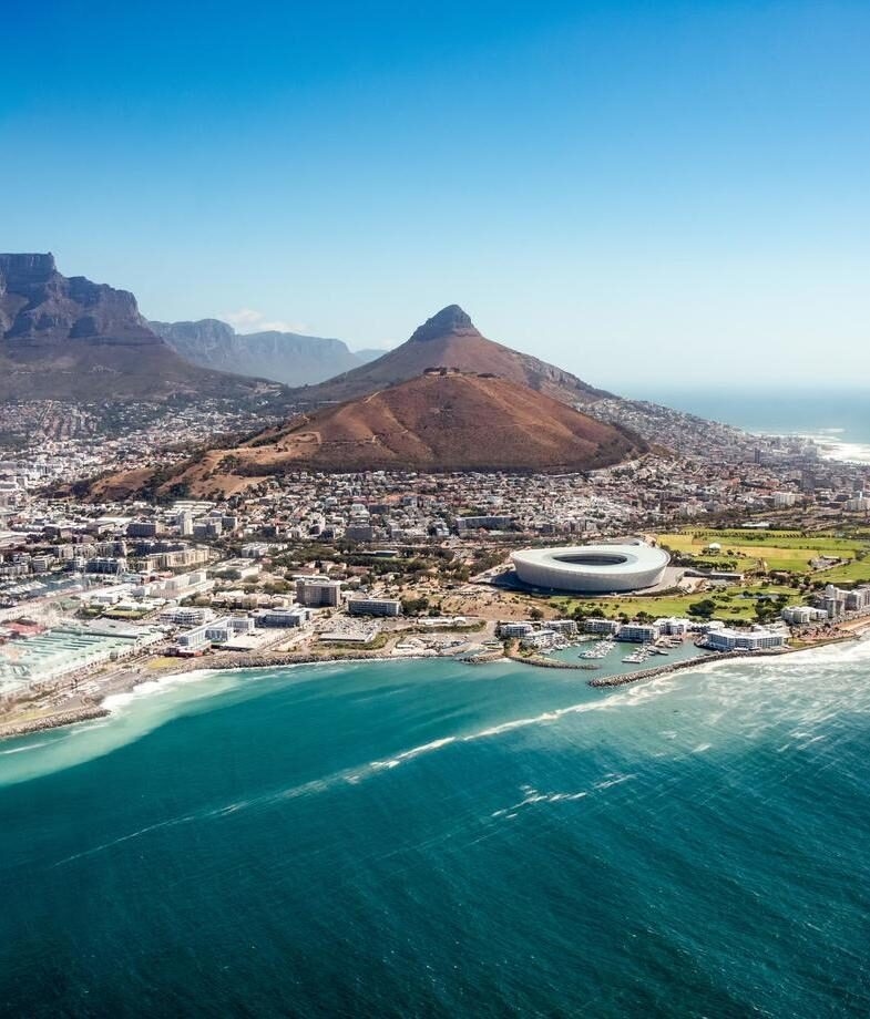 A sweeping view over Cape Town in South Africa, framed by the Atlantic coastline, and Sydney Harbour in Australia at sunset.