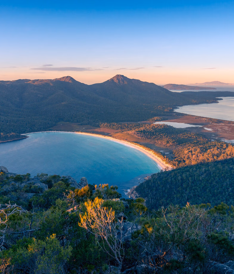 The red desert landscapes of Uluru–Kata Tjuta National Park, and the sweeping curve of white sand at Wineglass Bay in Freycinet National Park.