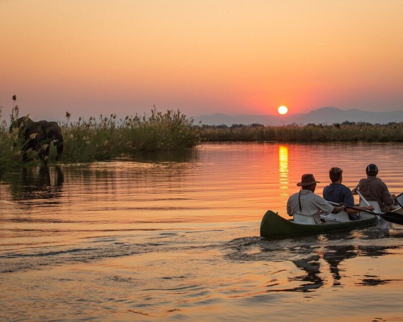 Three people in a canoe paddle across a calm river