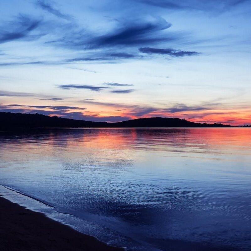 A serene sunset over Lake Victoria with hills silhouetted against a colorful sky.