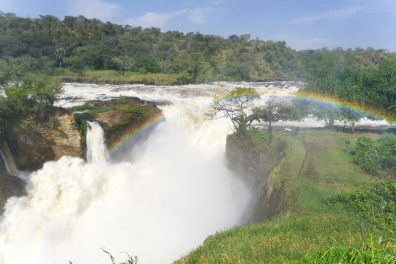 A wide shot of a powerful waterfall with a vibrant rainbow arching through the mist.