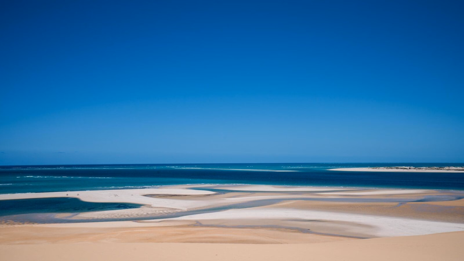 Wide view of sandbars and turquoise ocean water under a clear blue sky in the Bazaruto Archipelago, Mozambique.