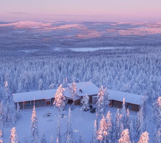 Aerial view of Octola Lodge at sunset surrounded by snow covered trees