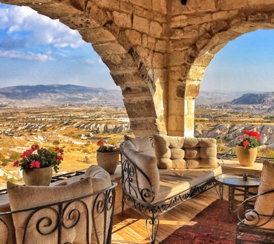 Stone arch terrace with plush seating and flowers overlooking the valley at the Museum Hotel in Turkey.