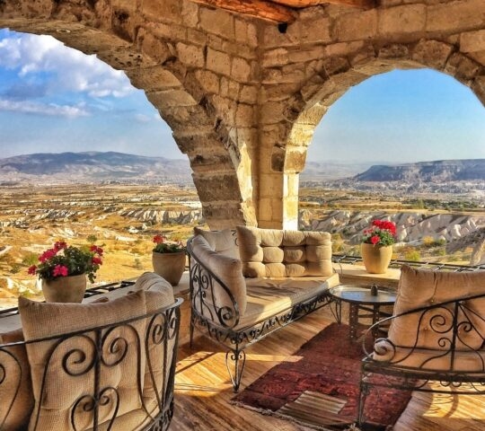 Stone arch terrace with plush seating and flowers overlooking the valley at the Museum Hotel in Turkey.
