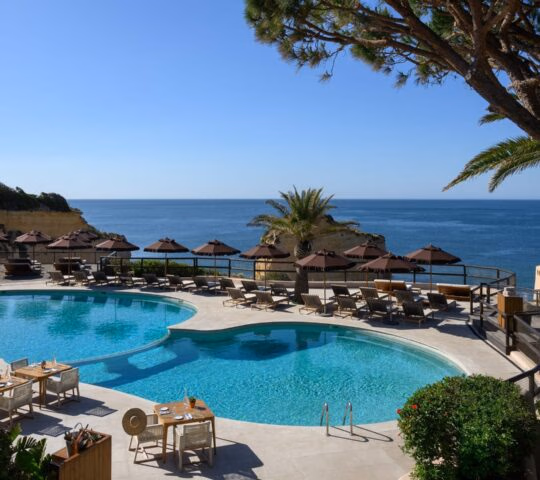 An outdoor swimming pool with sunbeds on a sea facing terrace at VilaLara Thalassa Resort in Portugal