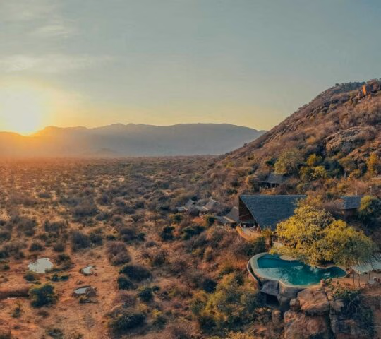 A high-angle view of green mountains and Reteti House tucked among rocks and dense vegetation.
