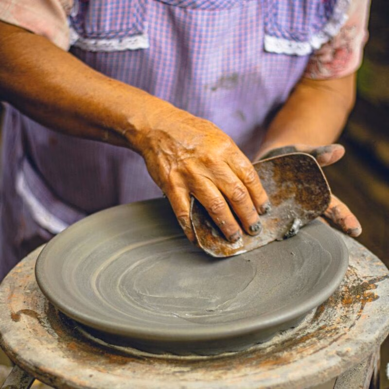 Close-up of hands shaping a clay plate on a pottery wheel in Mexico.