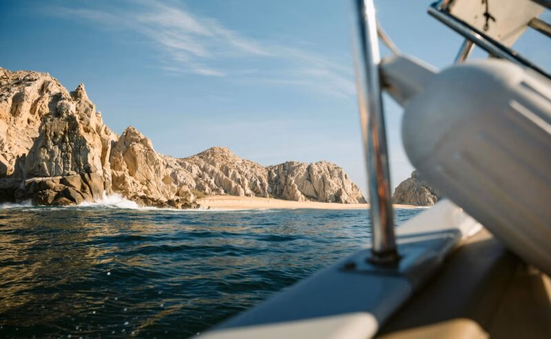 Coastal rock formations and a sandy beach seen from a boat during a Mexico family vacation.