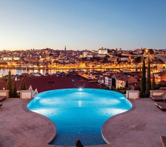 Infinity pool with terrace overlooking the city of Porto at dusk at The Yeatman hotel