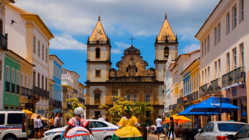 Traditional Bahian women walk past colonial buildings toward the Sao Francisco Church in Salvador, Brazil.