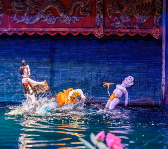Traditional Vietnamese water puppets depicting a scene with a tiger and a person on a dark water stage.