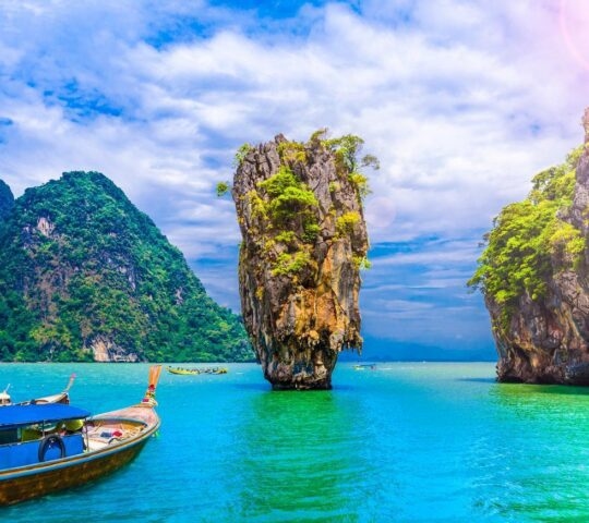 a traditional wooden boat floating on blue water with limestone karsts rising out of it