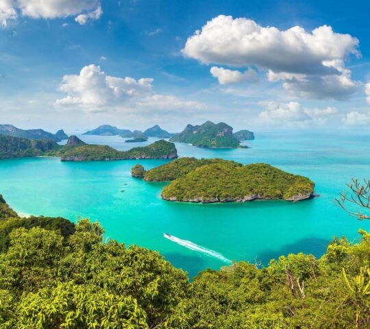 Aerial view of green forested islands surrounded by bright blue water in Ang Thong Marine National Park, Thailand
