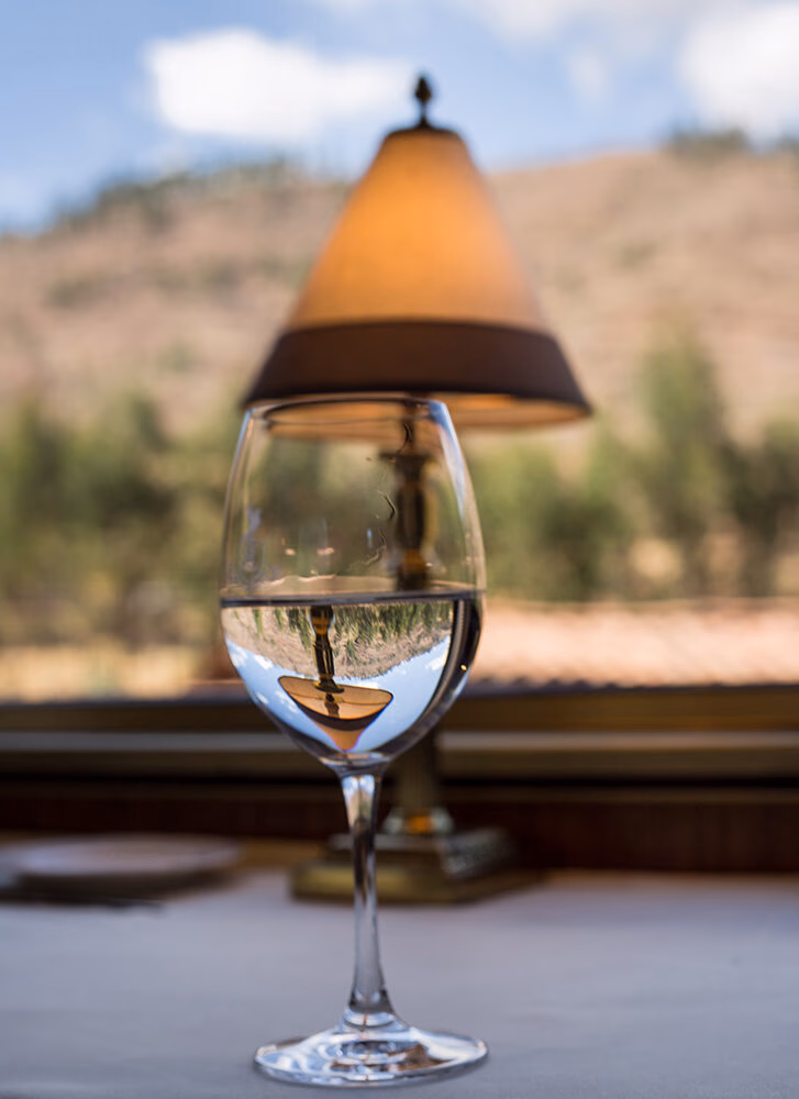 A water glass reflecting a lamp on luxury Peru train journeys.