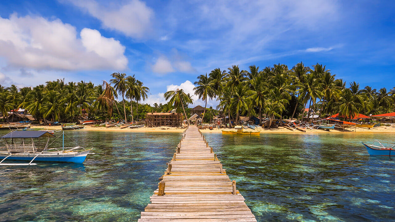 The wooden Cloud 9 surfing boardwalk extends over the shallow coastal waters of Siargao Island in the Philippines.