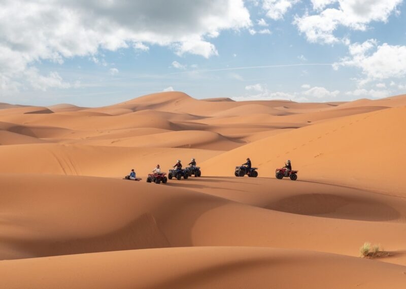 A group of people riding ATVs through sand dunes in the Moroccan Sahara