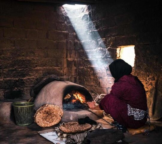 A Berber woman making bread in a traditional oven in Morocco