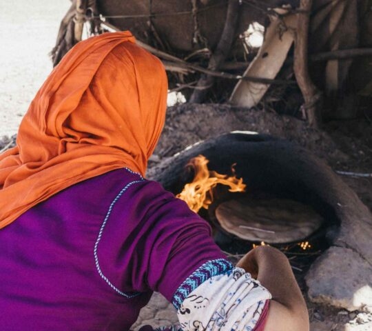 A Berber woman making bread in a traditional oven in Morocco