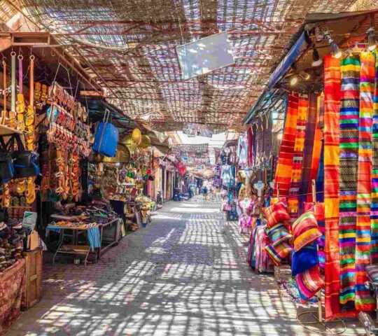 An alleyway lined with stalls selling colourful goods in the souks of Marrakesh