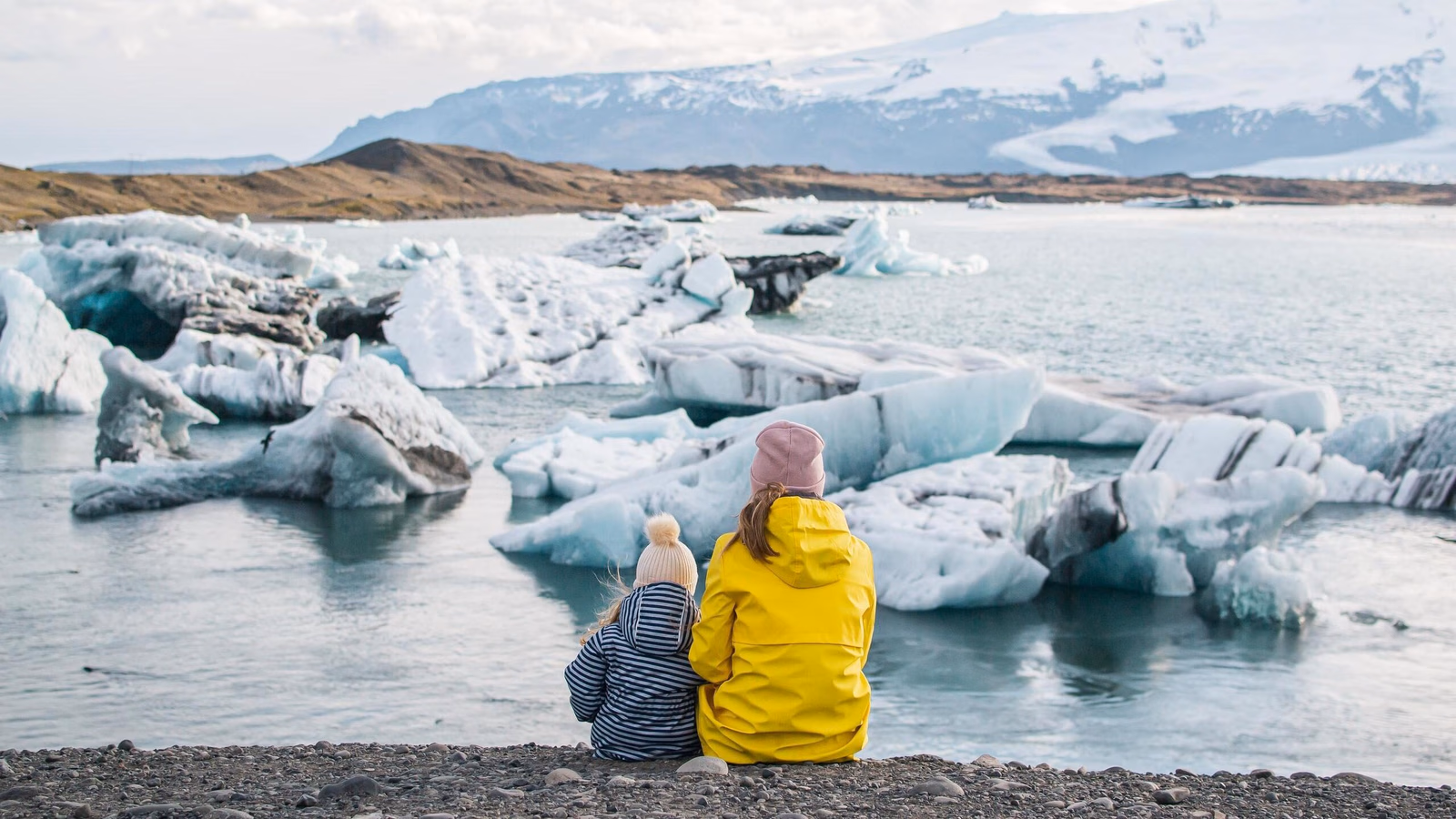 A mother and child sat side by side looking at a glacier in Iceland