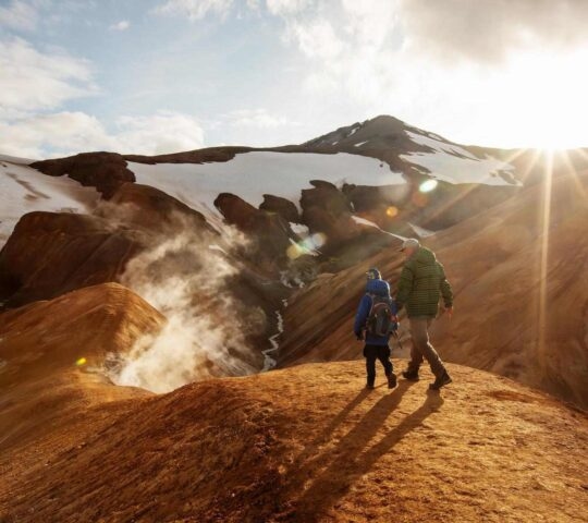 A father and son walking across golden hills in Iceland