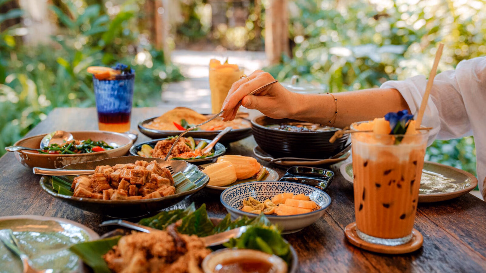 A full table of Thai vegetarian food with colourful dishes and plates.