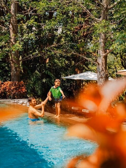 A father and son enjoy time in a swimming pool in Thailand.