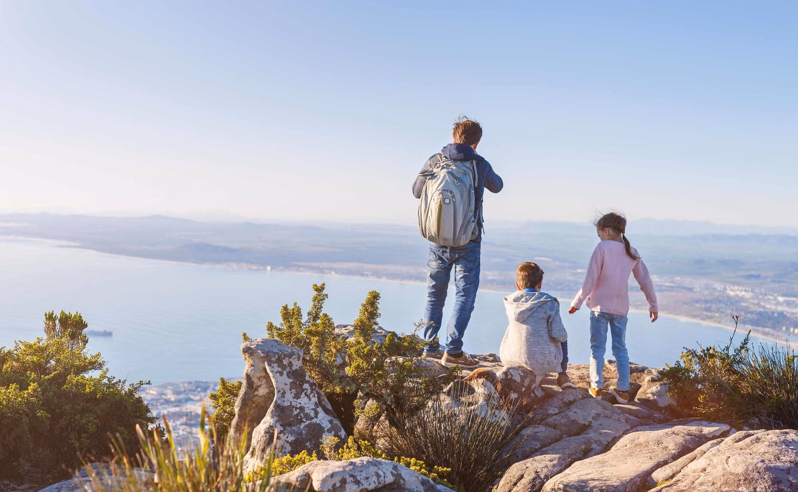 Three children admiring a view over Cape Town and the ocean from the top of Table Mountain
