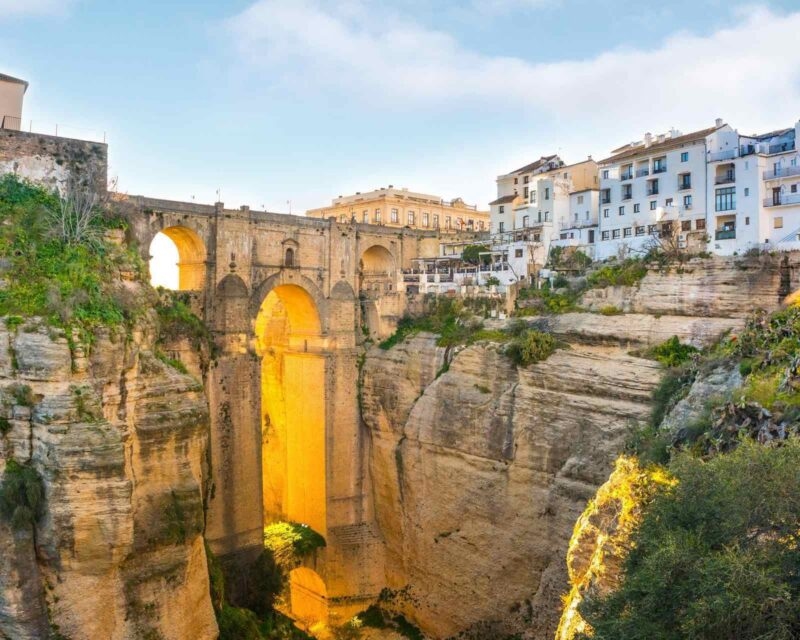 A stone bridge crossing a groeg running through the Old Town of Ronda in Spain