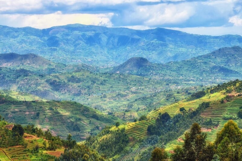 Scenic view of terraced green hills and lush valley landscapes under a cloudy blue sky.