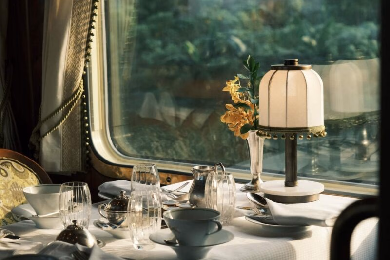 A dining table set up next to the train window inside the Belmond Eastern & Oriental Express