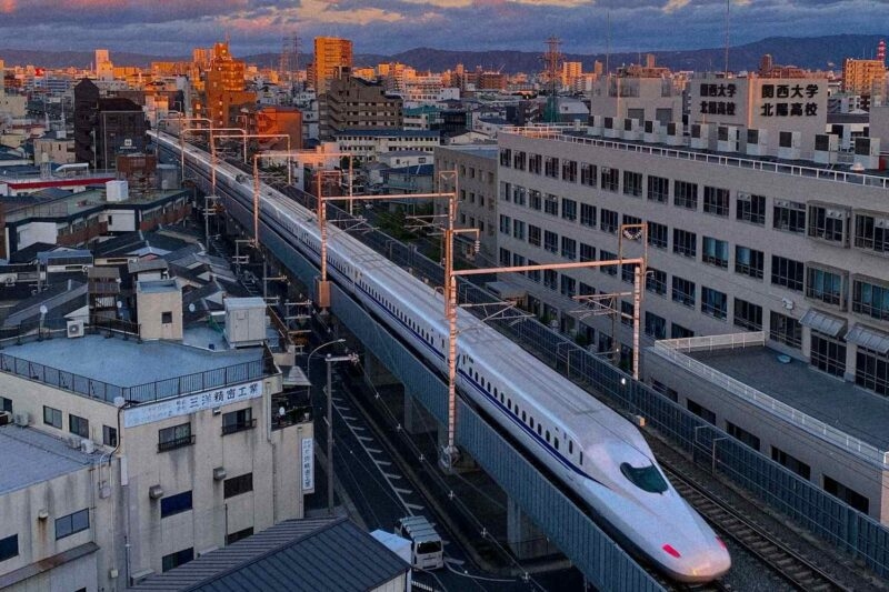 View of the Shinkansen railway travelling through a Japanese cityscape at sunset