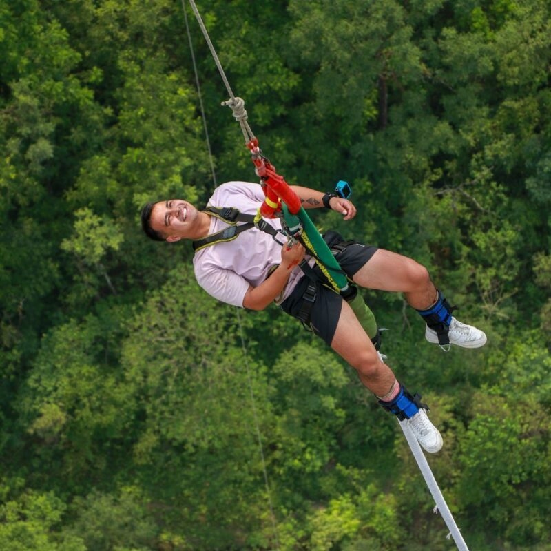 Smiling person suspended from a cable high above a green forest canopy during active costa rica.