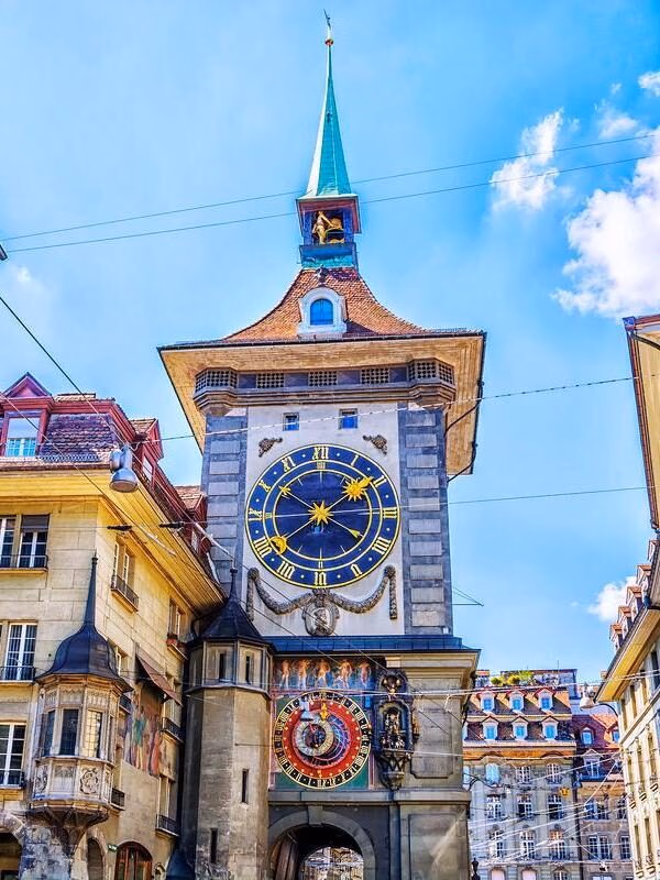 The Zytglogge medieval clock tower featuring a decorative astronomical clock face between historic buildings in Bern.