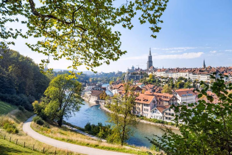 Skyline view of Bern Old Town with historic buildings, a winding river, and church spires under a clear blue sky.