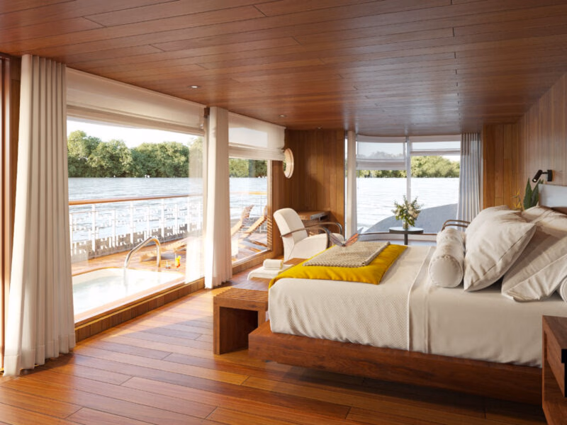 A luxury cabin on a latin america expedition cruise features a bed, large windows, and a private deck with a small pool.