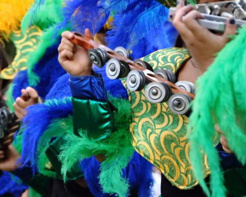 Close up of carnaval goers in Brazil wearing bright blue and green costumes and playing percussion instruments