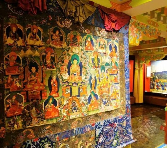 A display of thangka Buddhist artwork on a large hanging scroll