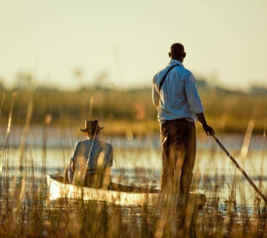 Two people in a traditional mokoro canoe on a river