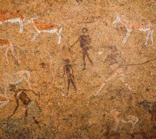 Ancient rock paintings of hunters and animals on a textured, earthy stone wall.