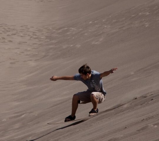 A man sandboarding down a sand dune in the Sahara desert