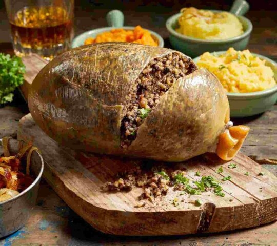 A sliced open haggis served with mashed potatoes and vegetables