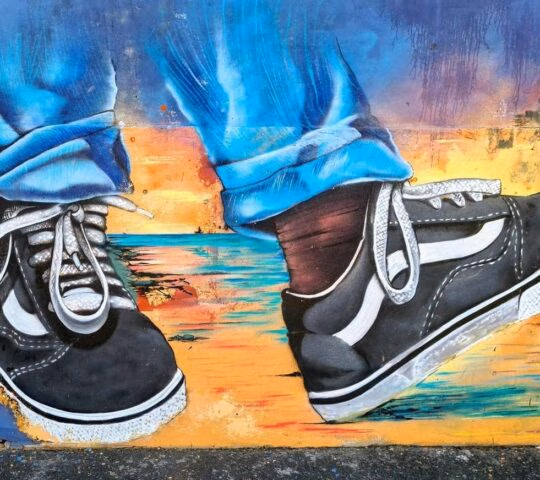 A colourful street art mural in Cape Town depicting a person's feet wearing a pair of trainers