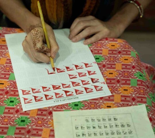 A woman practising letter writing at a Newari language workshop in Nepal