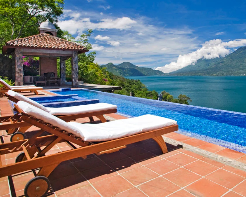 Sun loungers at Casa Palopo's infinity pool overlooking Lake Atitlan on a sunny day, Santa Catarina Guatemala