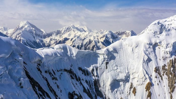 Aerial View of High Altitude Snowbound Mountains with Massive Glaciers Sharp Rock Ridges and Ice Slopes from Helicopter with Rotating Screw Blade