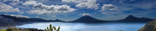 Panoramic view of Lake Atitlan in Guatemala, surrounded by mountain peaks on a sunny day