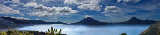 Panoramic view of Lake Atitlan in Guatemala, surrounded by mountain peaks on a sunny day